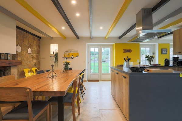 A modern kitchen with a wooden dining table, yellow chairs, and a kitchen island.