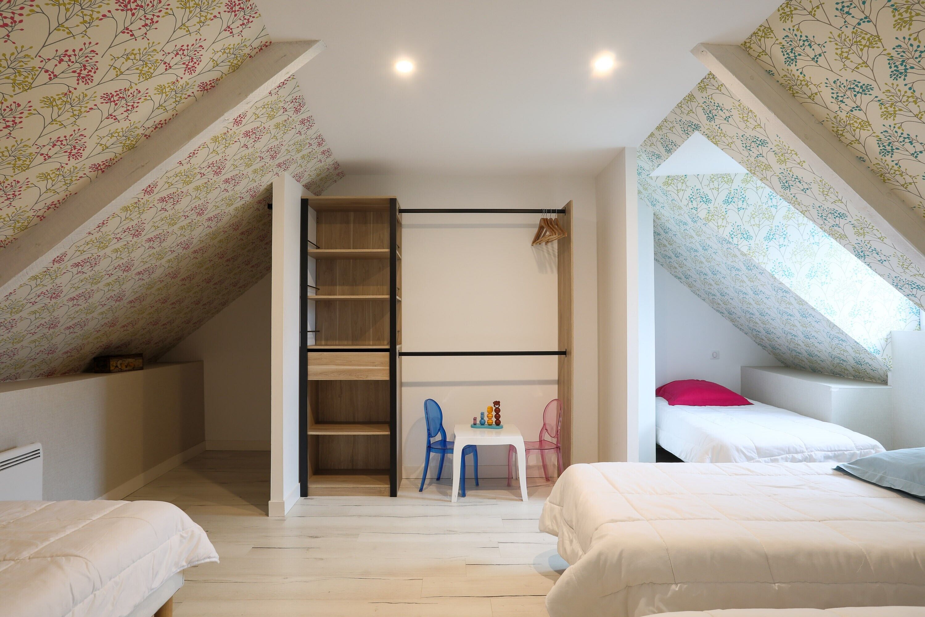 Un dormitorio con zona de dormir en entrepiso, una mesita con sillas y un armario.