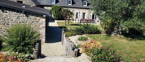 A stone building with a gravel pathway leading to a covered area.