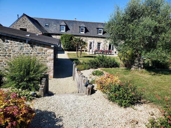 A stone building with a gravel pathway leading to a covered area.