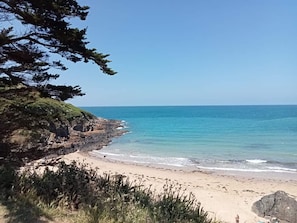 A coastal beach with clear skies, a rocky shoreline, and a sandy beach.
