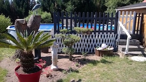 A backyard with a pool, a wooden fence, and various potted plants.