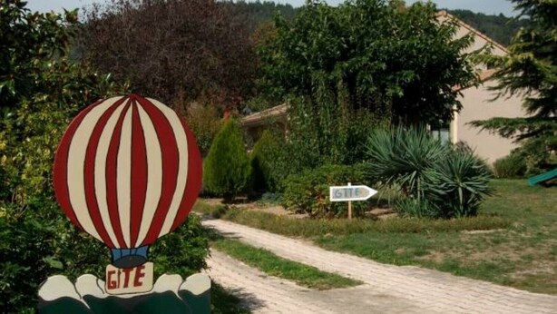 A sign with a hot air balloon and the word "GITE" pointing to a path.