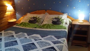 A bedroom with a starry wall, a bed with patterned bedding, and bedside lamps.
