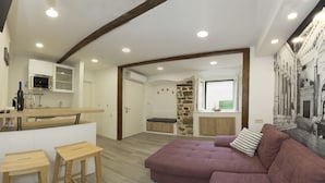 Una cocina moderna con horno empotrado, pared decorativa de piedra y una zona de estar acogedora con sofá morado y taburetes de madera.