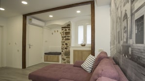 Una sala de estar moderna con un sofá seccional grande, una pared de acento de piedra y vistas a un paisaje urbano a través de una ventana.