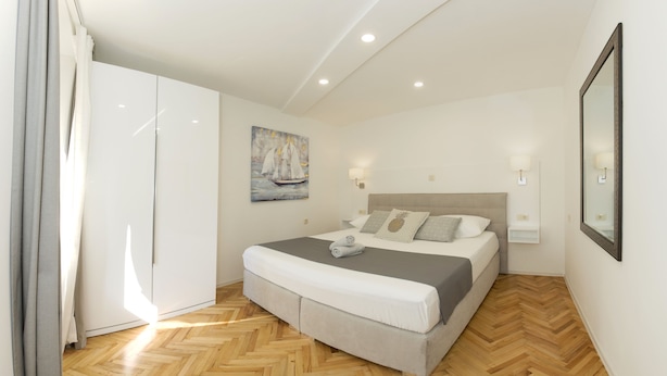 Un dormitorio con cama, armario, cuadro y espejo.