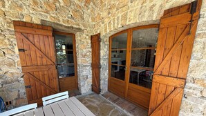 Una habitación con paredes de piedra, puertas de madera y una mesa.