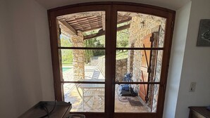 Una habitación con ventanal de esquina, una mesa de metal y una pared de piedra.