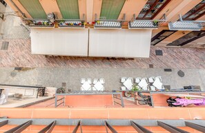 Une terrasse sur le toit dotée de plusieurs espaces de détente, notamment des tables et des chaises, et un vélo garé sur le côté.