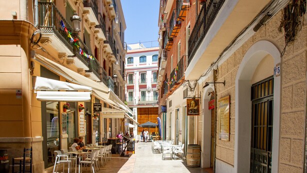A narrow street with outdoor seating and buildings on either side. - Julia Centro Historico (Málaga)