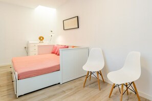 Une chambre à coucher avec un lit, deux chaises, une table de chevet, une lampe et un tableau encadré au mur.