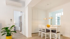 A dining area with a white table and chairs, a potted plant, and pendant lighting. - Julia Centro Historico (Málaga)