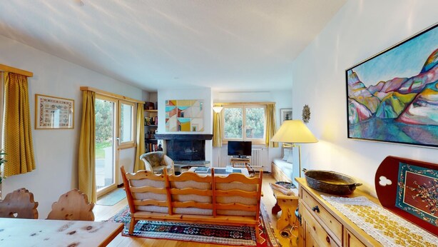 Ein gemütliches Wohnzimmer mit Kamin, Essbereich und einer Küche im Hintergrund.