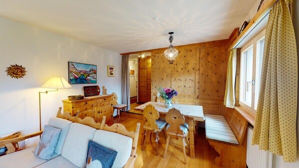 Un interior de madera acogedor con comedor, sofá y una araña.