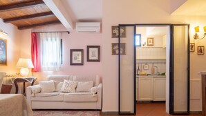 Un soggiorno con un divano, un tavolo e una cucina visibile attraverso una porta aperta.