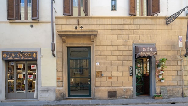 Un edificio con una vetrina che reca l'insegna 'LA ROSA' e un altro con il cartello 'RISTORANTE CINGI'.