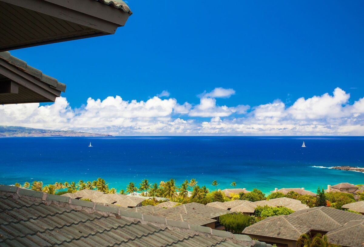 A coastal view with clear skies, a turquoise sea, and a distant island.