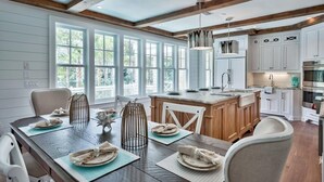 Una cocina moderna con vigas de madera, armarios blancos y una isla grande.