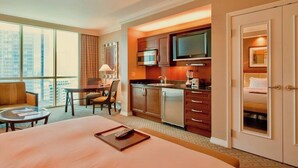 A hotel room with a large bed, a desk with a chair, a kitchenette, and a TV. - No Resort Fee | Strip Views, Pools & Parking (Las Vegas)
