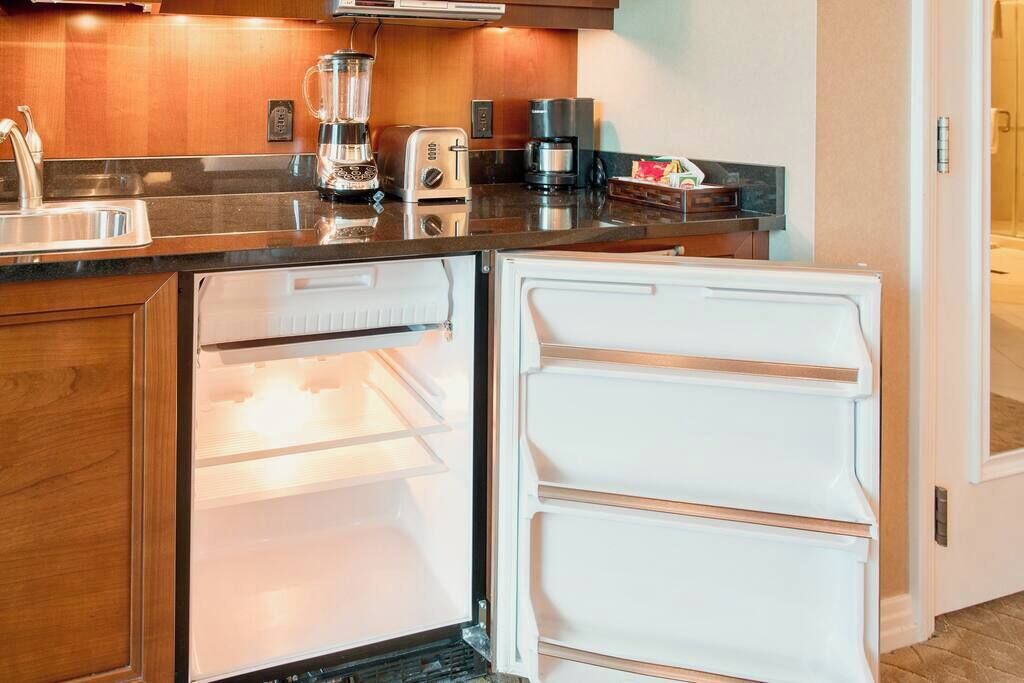 A compact kitchen with a refrigerator, a coffee maker, and a toaster.