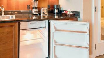 A compact kitchen with a refrigerator, a coffee maker, and a toaster.