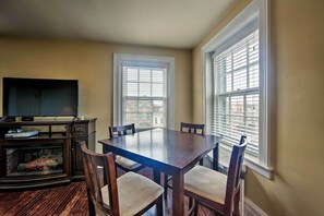 A dining area with a wooden table and chairs, a television, and a fireplace. - Walk to Shops, Dining & City Park: Reading Apt (Reading)