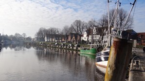 Un río tranquilo con barcos amarrados a la orilla, rodeado de edificios residenciales.