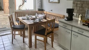 Una cocina con mesa, sillas, cafetera y alacenas.