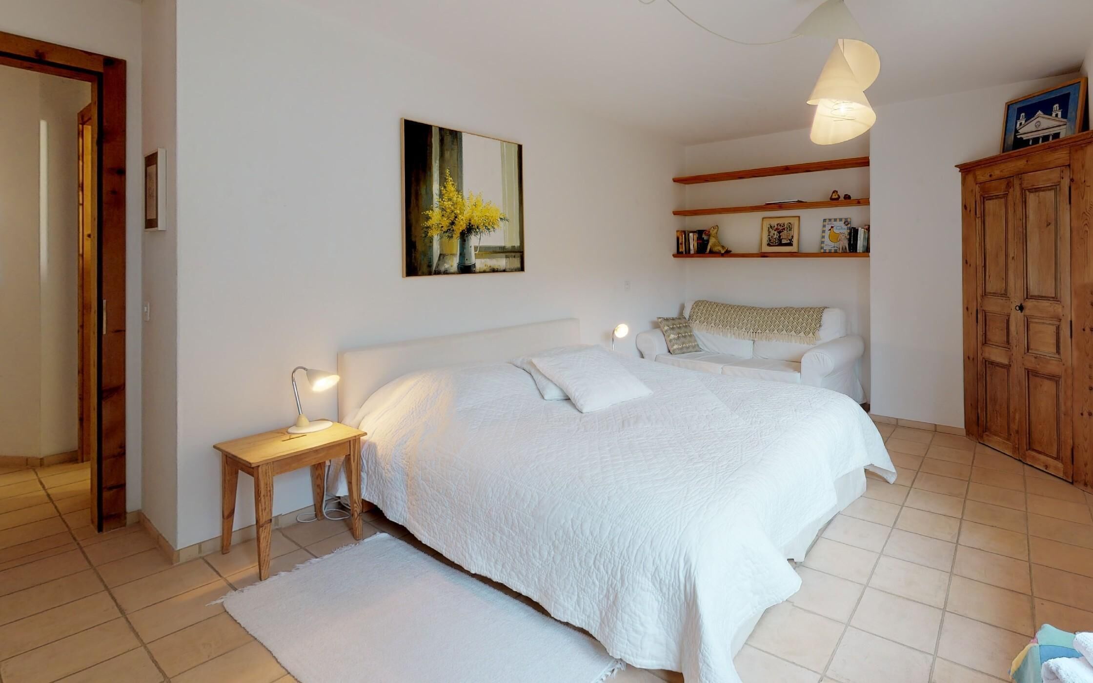 Une chambre à coucher avec un grand lit, des tables de chevet, une commode, une armoire en bois et un tableau au mur.