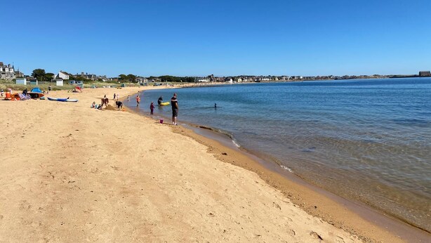 Une plage avec des gens, des bateaux et des maisons en arrière-plan.