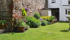 Un bâtiment en pierre avec un jardin à l’avant.