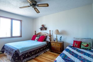 A bedroom with a bed, a nightstand, a dresser, a ceiling fan, and a window.