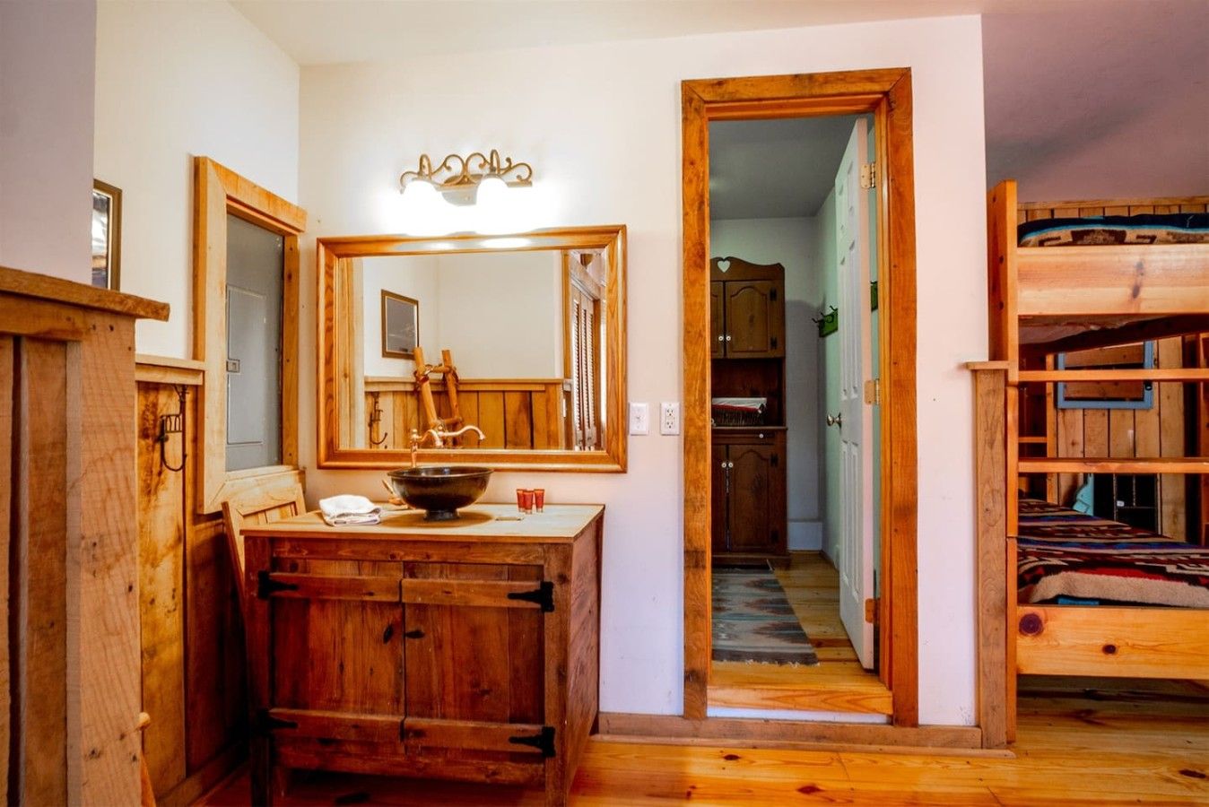 Un baño de madera con un espejo grande, un mueble de tocador de madera y un lavamanos.