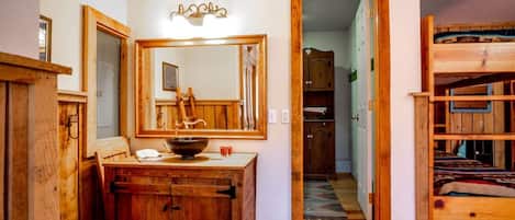 A wooden bathroom with a large mirror, a wooden vanity, and a sink.