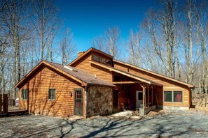 A wooden cabin with a stone foundation, a porch, and a clear view of the surrounding forest. - Dancing Bear - Private Wooded Lot, Dog Friendly (Davis)