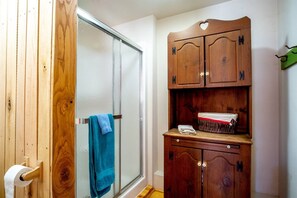 A bathroom with a wooden door, a towel hanging on a rack, and a wooden cabinet with a basket.