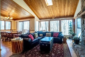A spacious living room with a large sectional sofa, a dining table, and a fireplace.