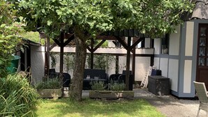A patio area with a pergola, outdoor seating, and a grill.