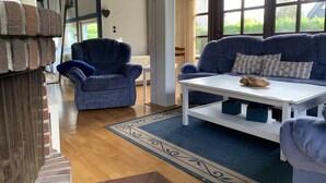 A modern living room with a blue sofa, a matching armchair, and a white coffee table. A patterned rug is on the wooden floor.