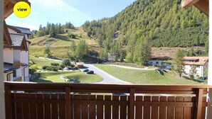 Un balcón con vistas a un paisaje rural, que incluye una carretera, casas y una colina boscosa.