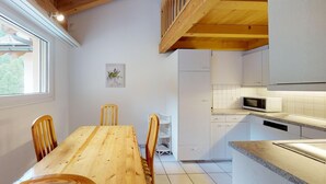 Una cocina con armarios blancos, una mesa de comedor de madera y un microondas.