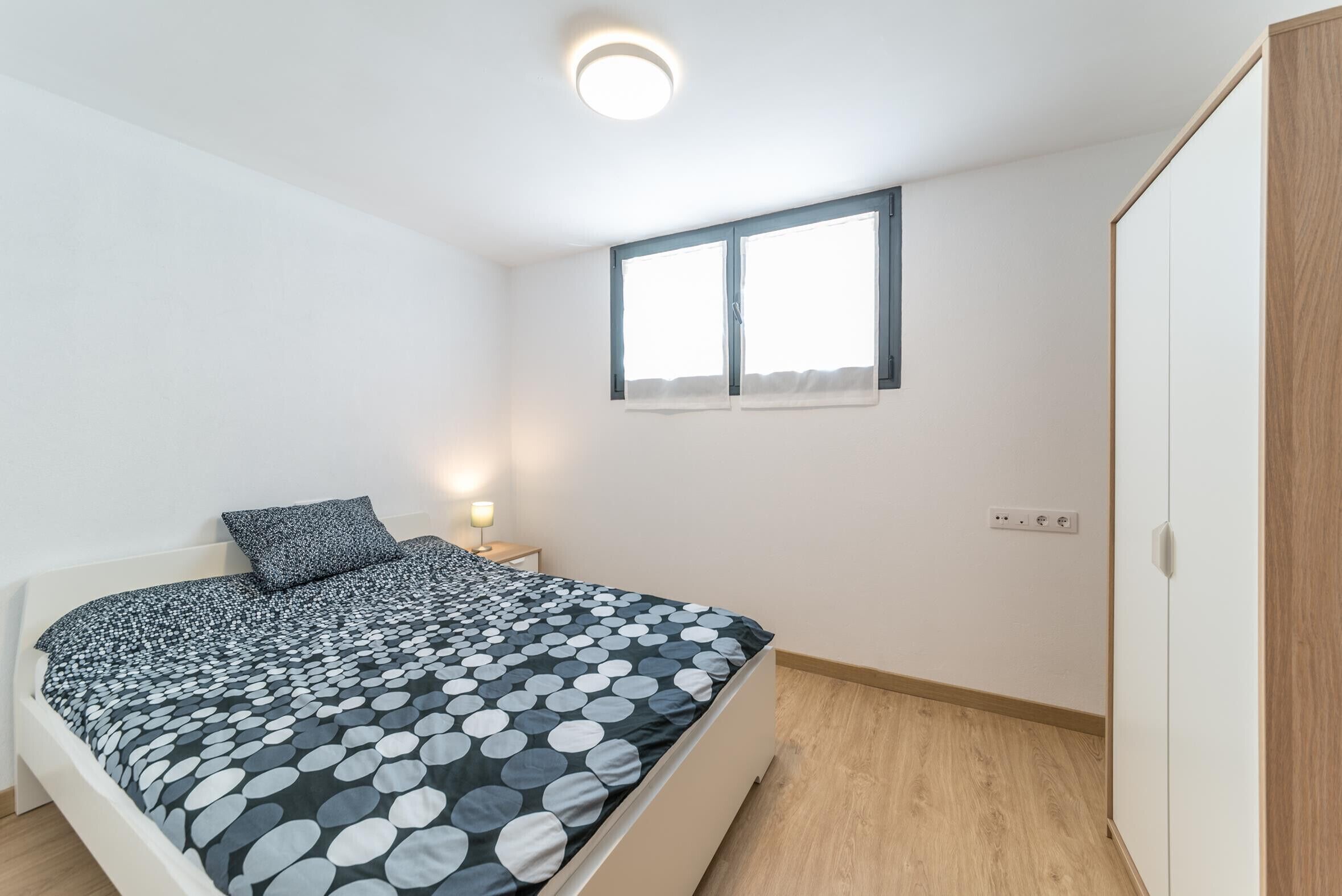 Ein Schlafzimmer mit Bett, Nachttisch, Fenster und Kleiderschrank.