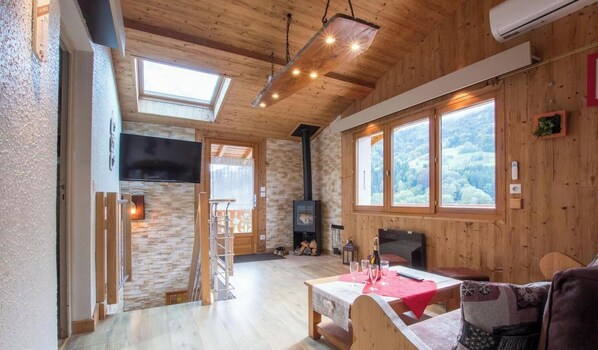 Una habitación acogedora con chimenea, paredes de madera, un altillo y ventanas amplias.