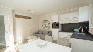 A modern kitchen with white cabinets, a black countertop, and a built-in oven. - Apartment near the beach with Patio and Garden (Novalja)