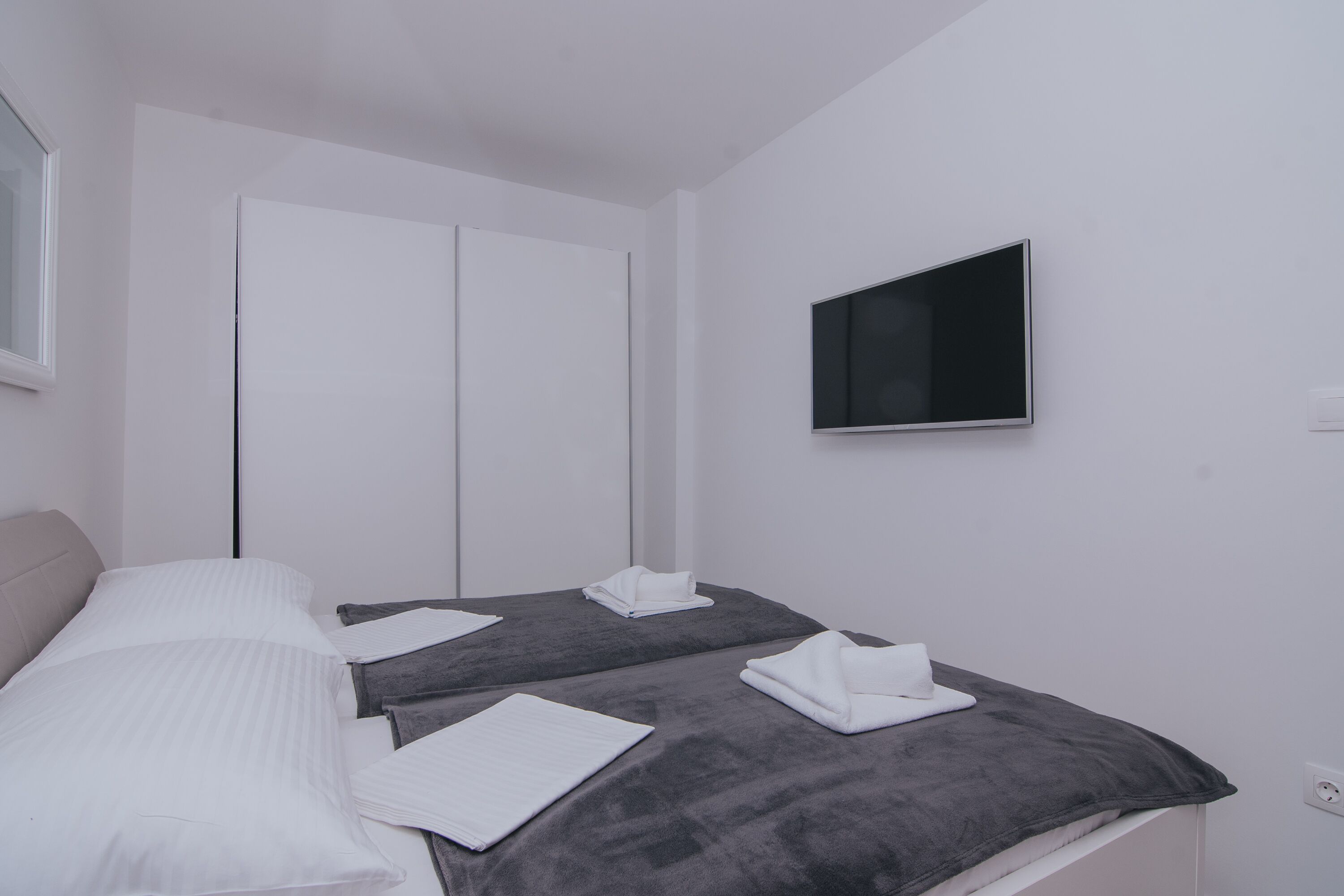 Una habitación de hotel moderna con dos camas, un televisor de pantalla plana montado en la pared y un ventanal amplio.