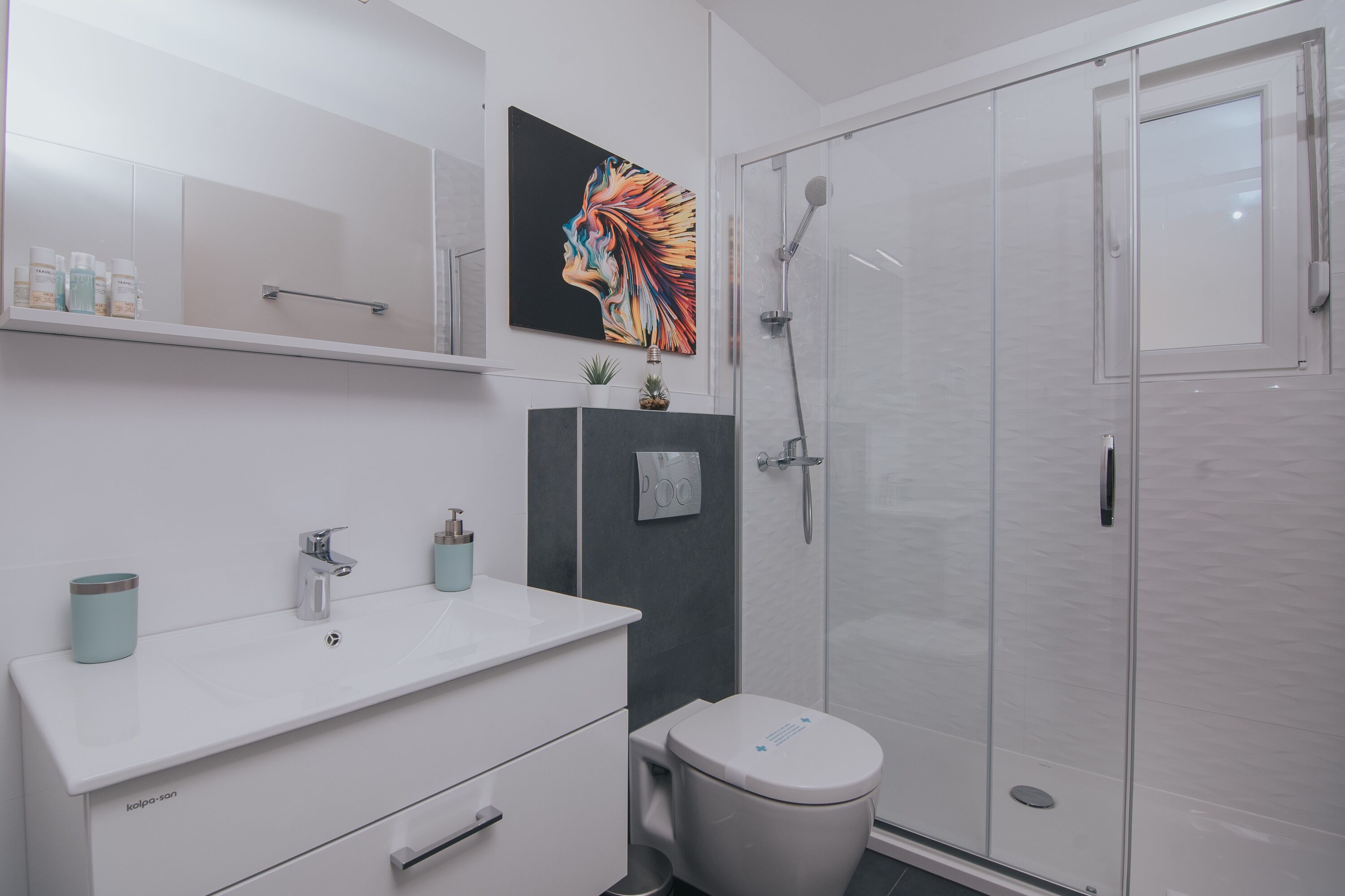 A modern bathroom with a white sink, mirror, and toilet.