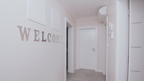 En hall med en skylt som visar texten ”VÄLKOMMEN”, en dörr och en vit vägg.