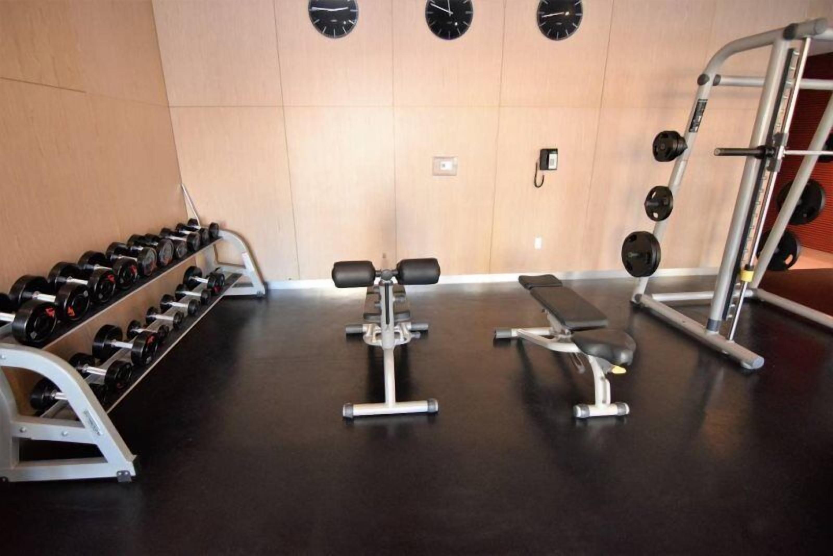 Une salle de sport équipée d’haltères, d’un banc et de matériel de musculation.