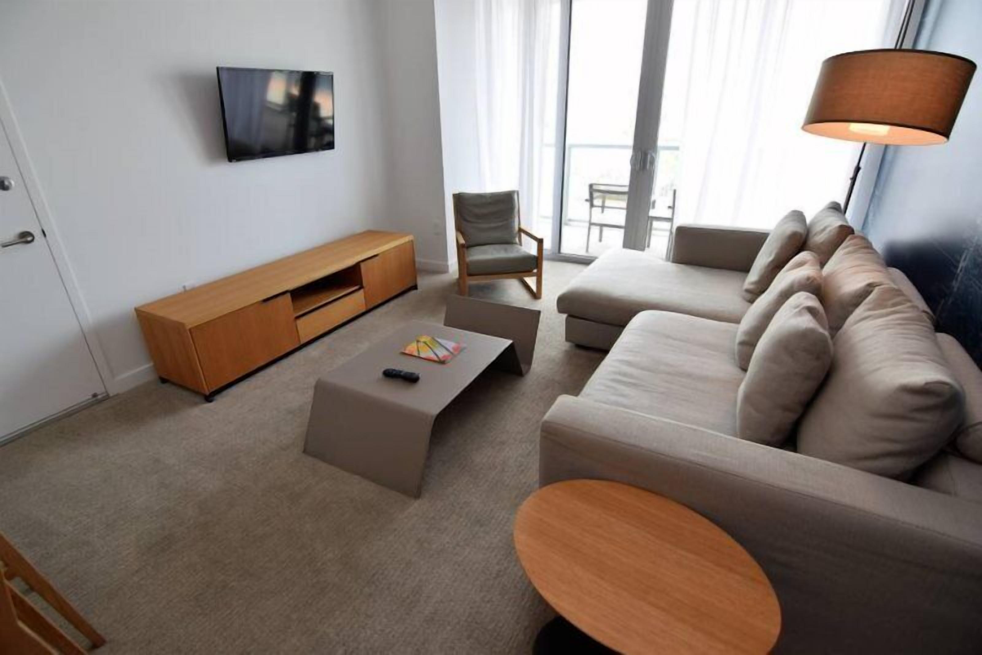 A modern living room with a sofa, a coffee table, a TV, and a chair.